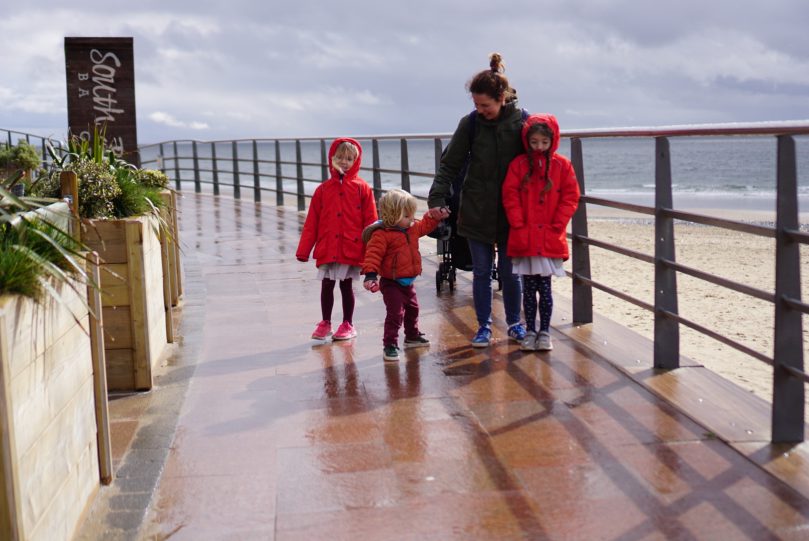 Mu and three children all in wintercoats on a rainy day
